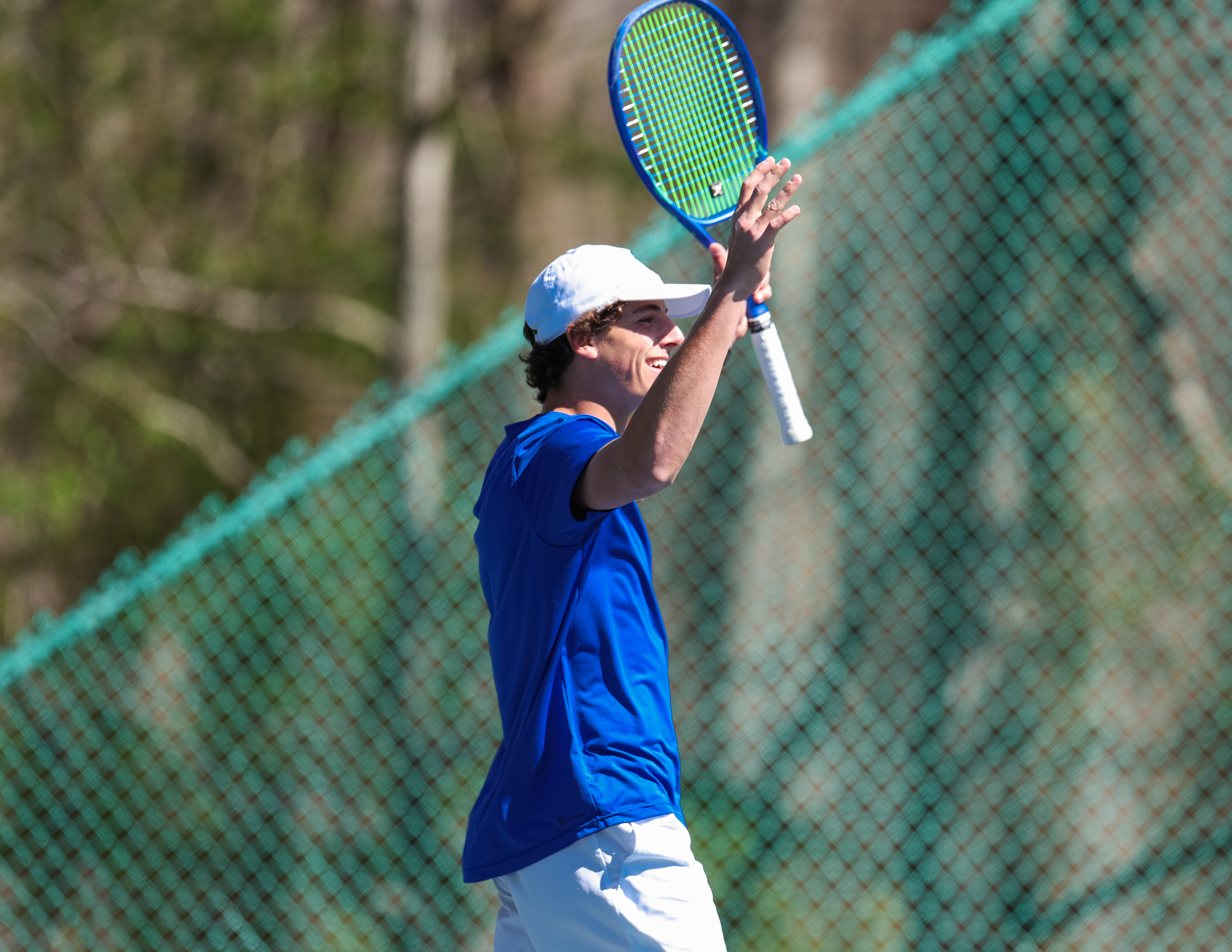 Trevor Gray smiling on court with his racquet raised after a tennis point.