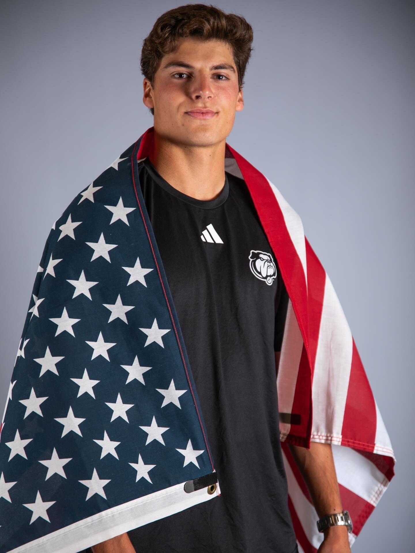 Trevor Gray wearing a UNC Asheville shirt with an American flag draped over his shoulders.